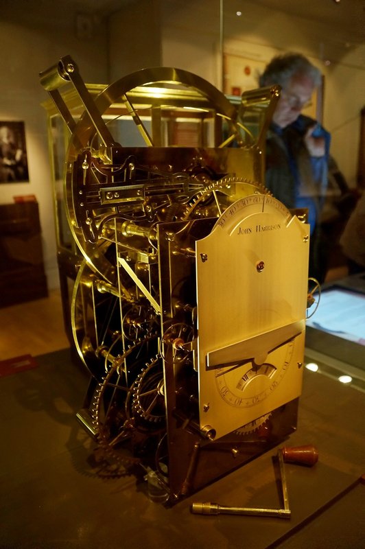 Harrison's H3 marine timekeeper, a tall brass machine, in a museum case